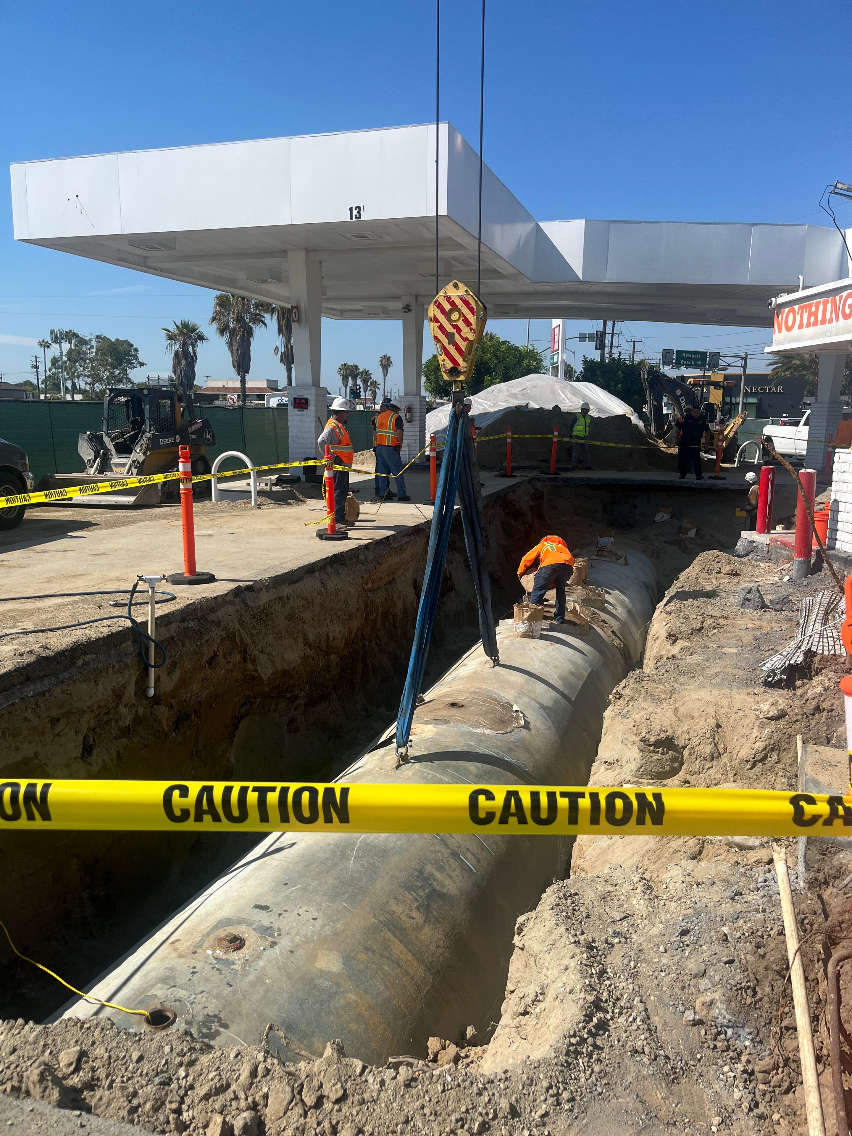 Construction crew installing a large underground pipe at a roadway work site